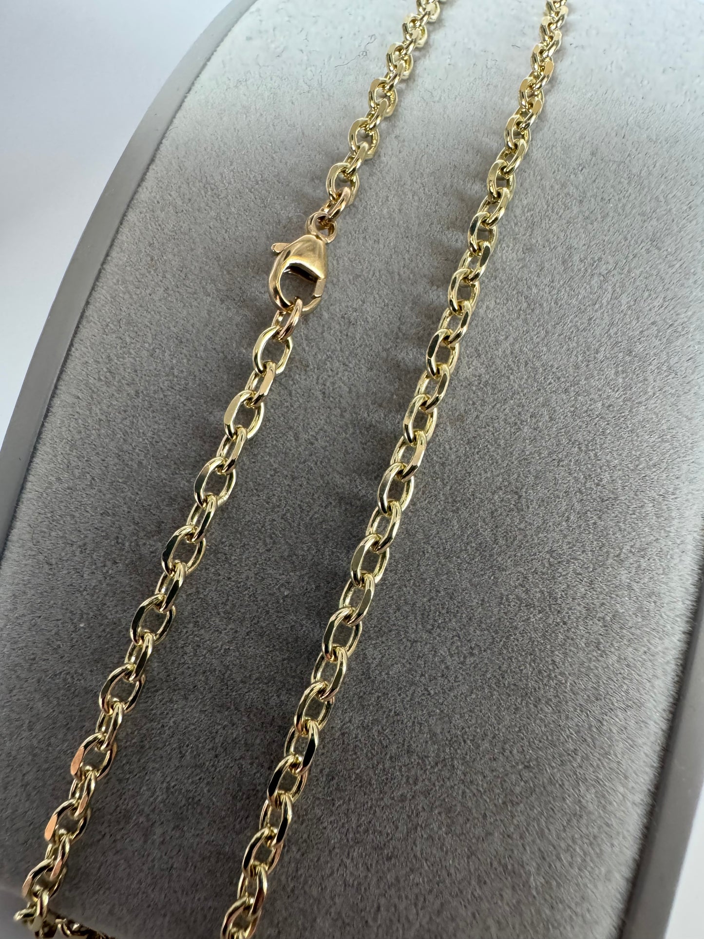 Gold chain necklace on a gray mannequin bust
